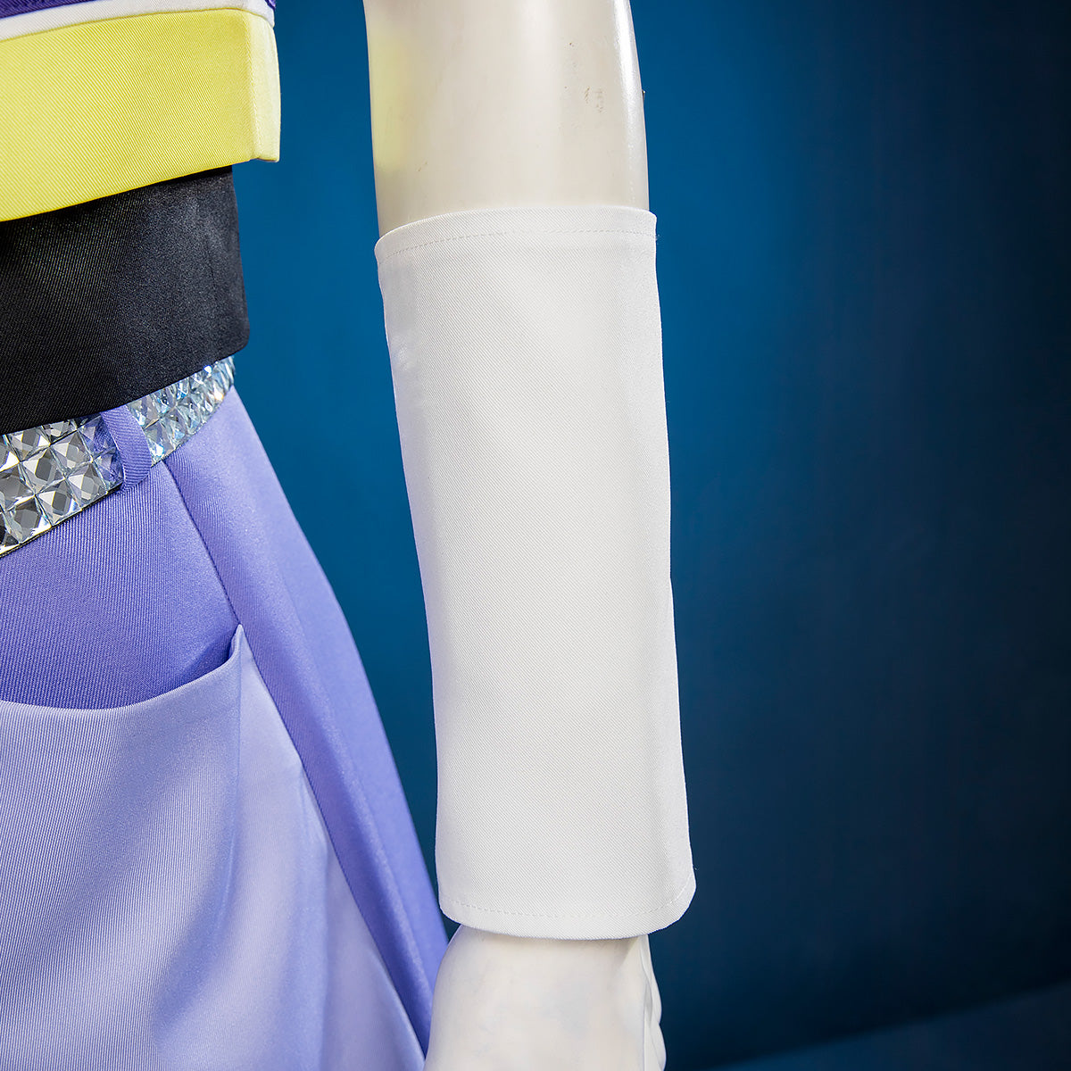 Close-up of Riku white forearm cuff on a mannequin beside the purple trousers