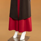 Front hem detail of the Mai dark outer layer over red wide-leg trousers