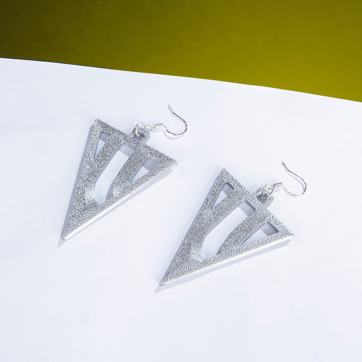 Pair of silver-colored triangular Jubilee cosplay earrings with cutout details displayed on white