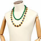 Blackbeard Marshall D. Teach green beaded necklace and longer blue-and-gold-colored necklace displayed on a mannequin