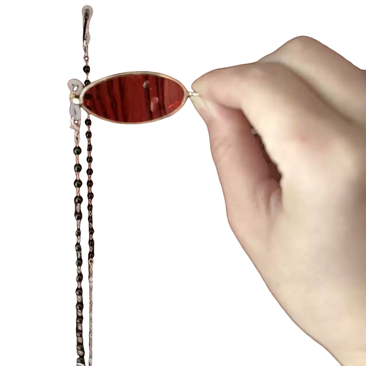 Hand holding the Alastor oval red-lens cosplay eyewear beside its hanging beaded chain