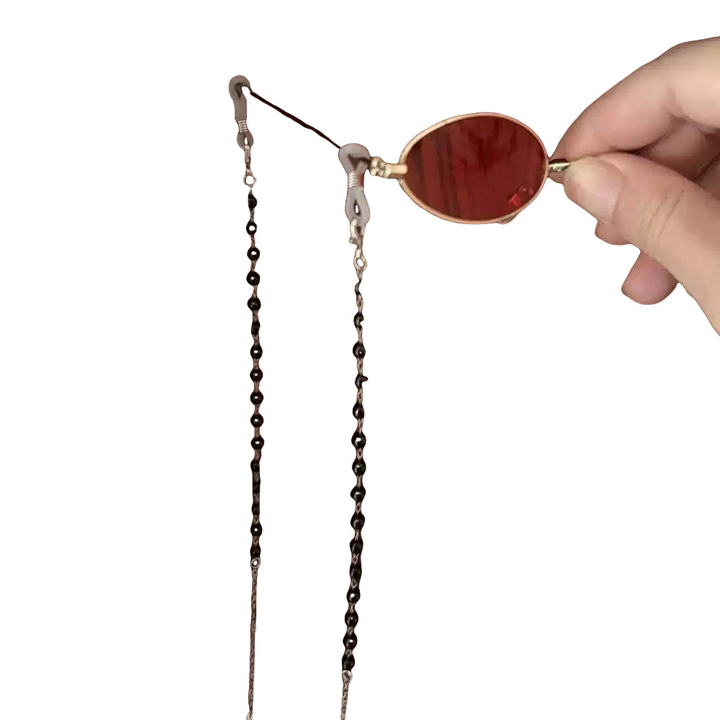 Angled handheld view of the Alastor red eyewear prop showing its nose pads and chain attachments