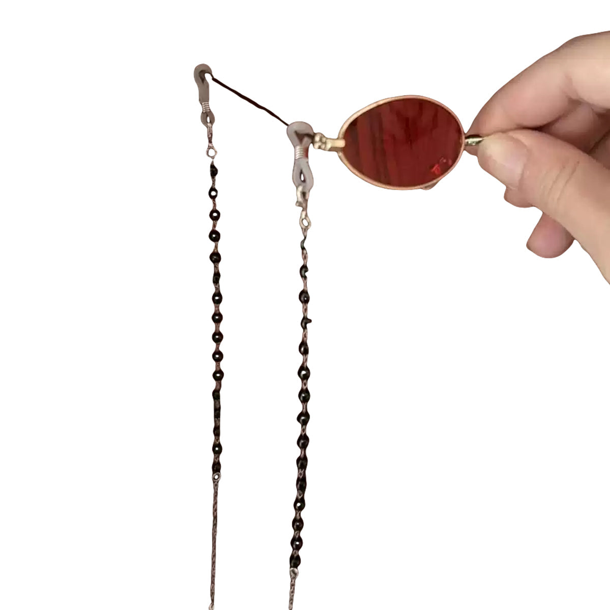 Angled handheld view of the Alastor red eyewear prop showing its nose pads and chain attachments