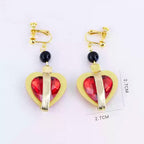 Crimson Priestess clip-on earrings with red heart-shaped ornaments, gold-tone frames and black beads, with 2.7 cm labels