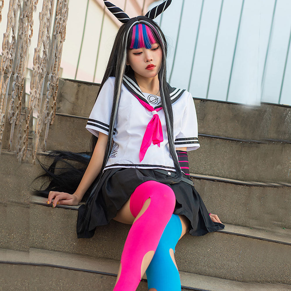 Seated model wearing the Ibuki Mioda white sailor top, black skirt and contrasting pink and blue stockings