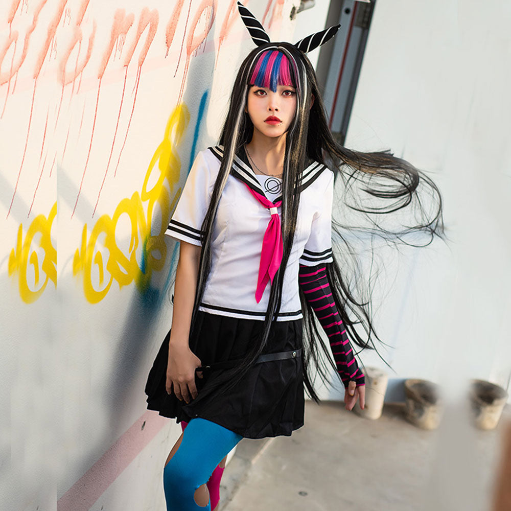 Model wearing the Ibuki Mioda sailor costume against a painted wall, with a pink necktie and striped arm warmer